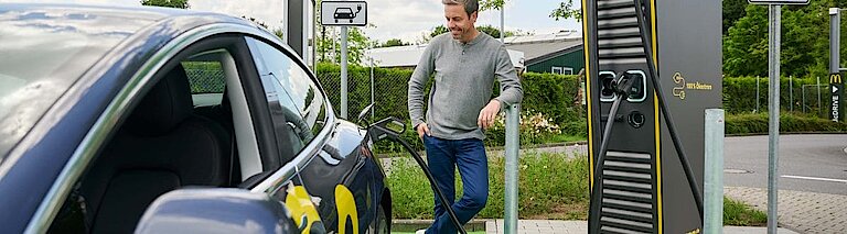 Mann betankt Elektroauto an einer EWE Go Schnellladesäule mit Strom.