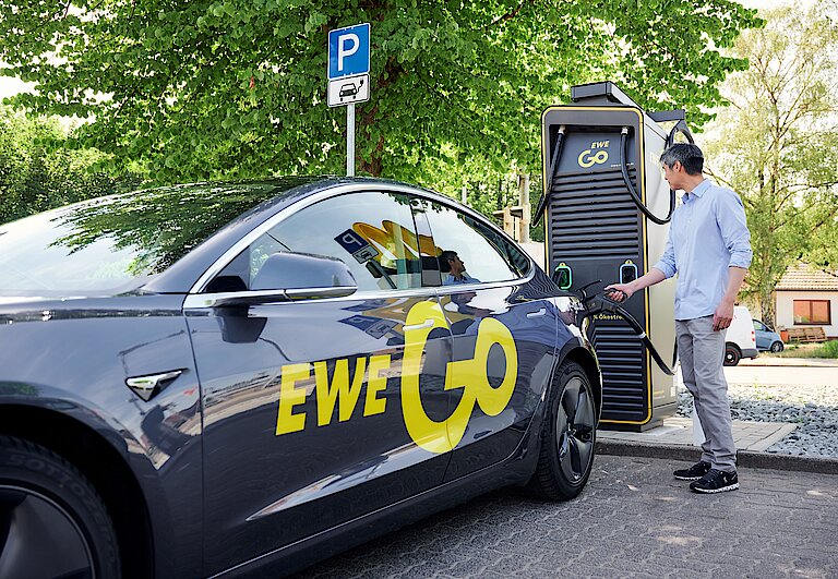 Mann betankt Elektroauto an einer EWE Go Ladesäule
