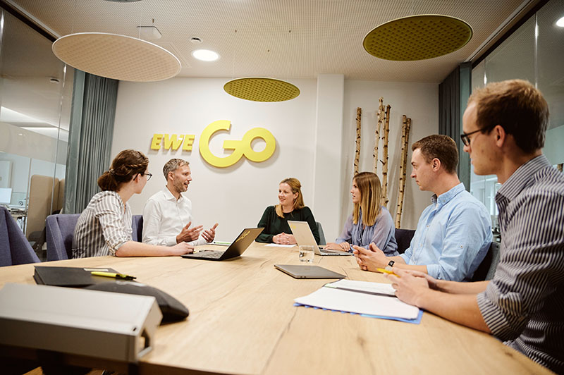 EWE Go-Mitarbeiter diskutieren in einem Konferenzraum miteinander